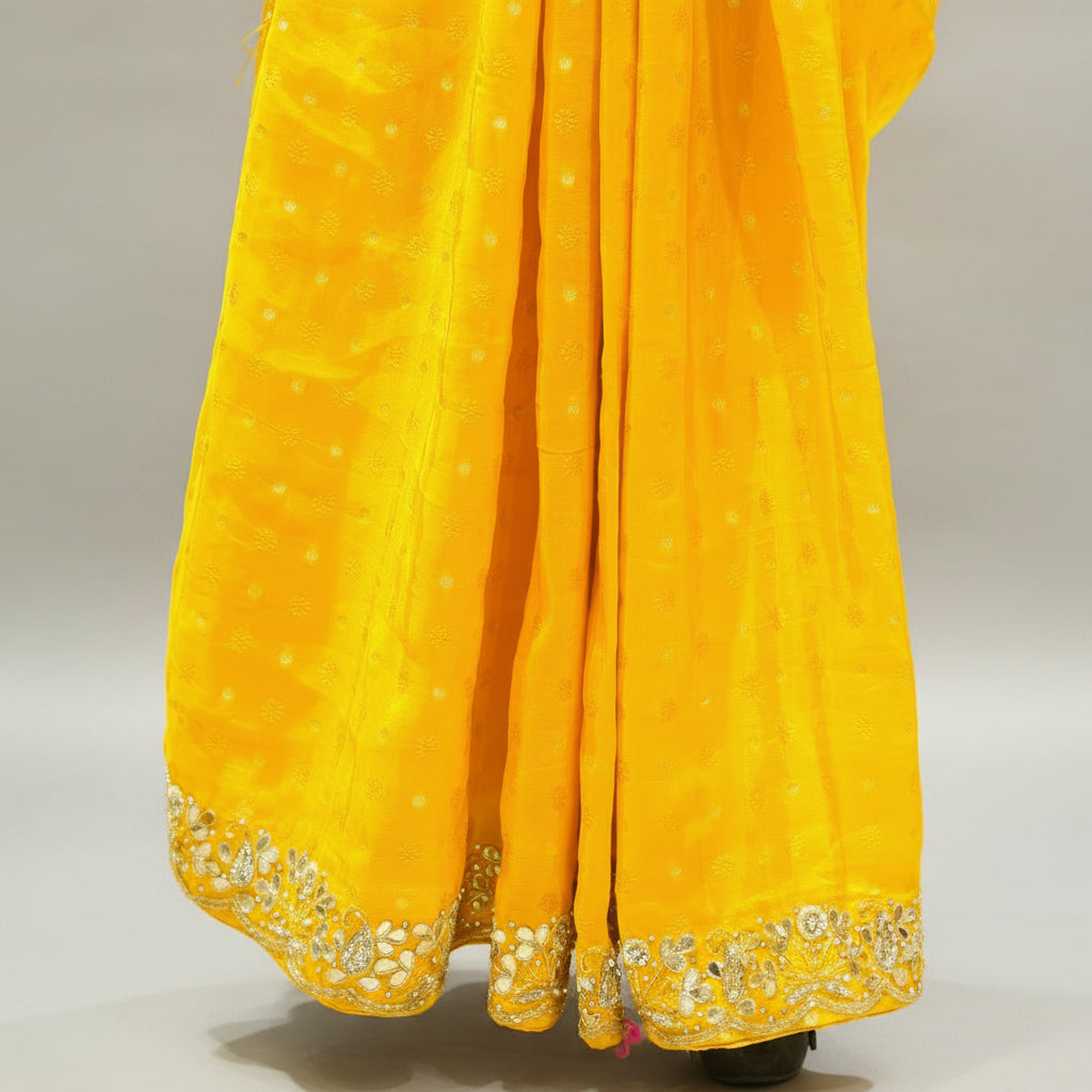 Yellow saree with intricate border on a white surface