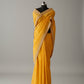 Yellow saree on a mannequin in a store setting with various products in the background.