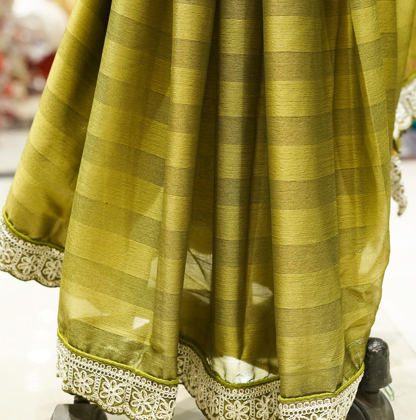Green saree with white border on a mannequin in a store setting