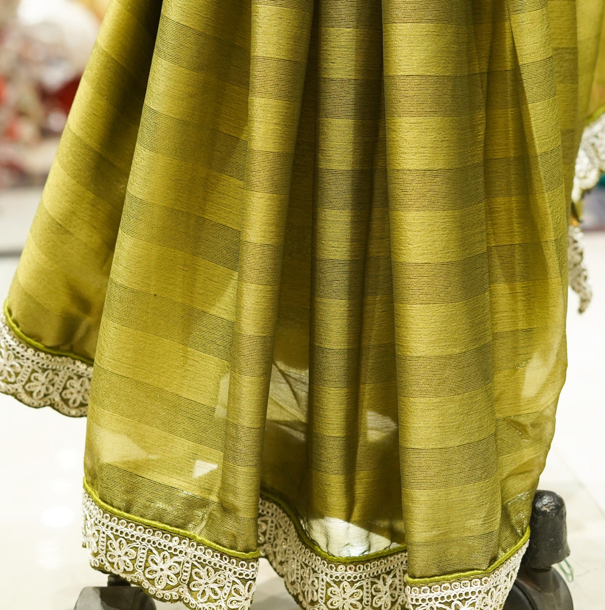Green saree with white border on a mannequin in a store setting