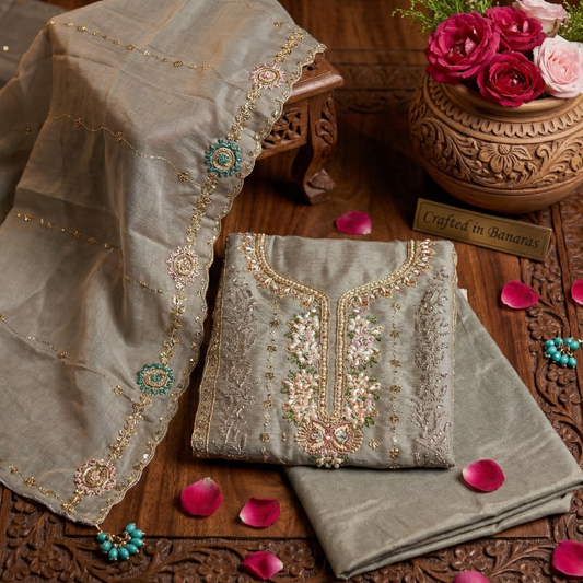 Embroidered fabric on a wooden surface with flowers and decorative elements.