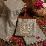 Embroidered fabric on a wooden surface with flowers and decorative elements.